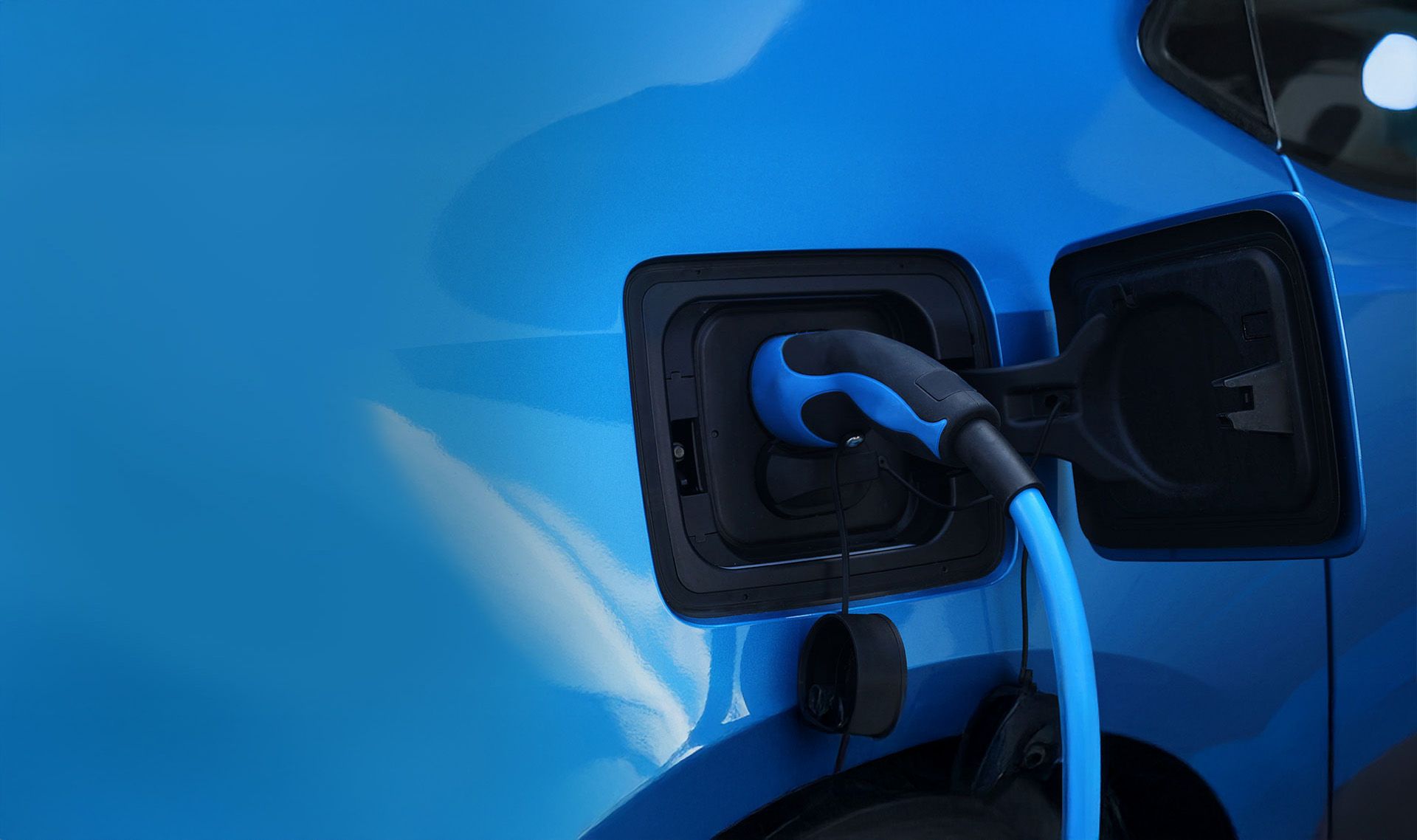 Ein blaues Elektrofahrzeug ist an einer Ladestation angeschlossen.